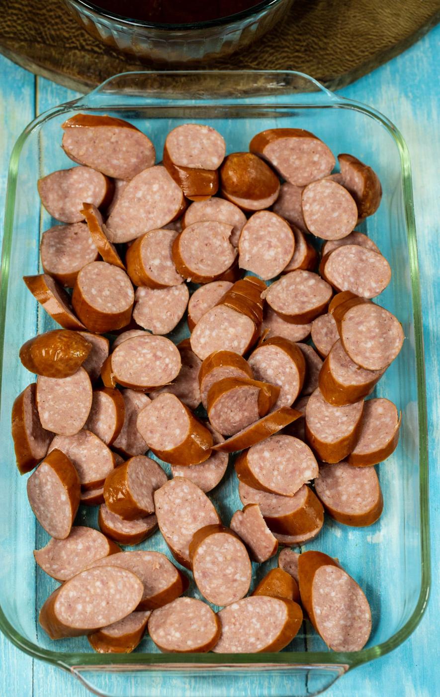 Uncooked sausage slices in baking dish.