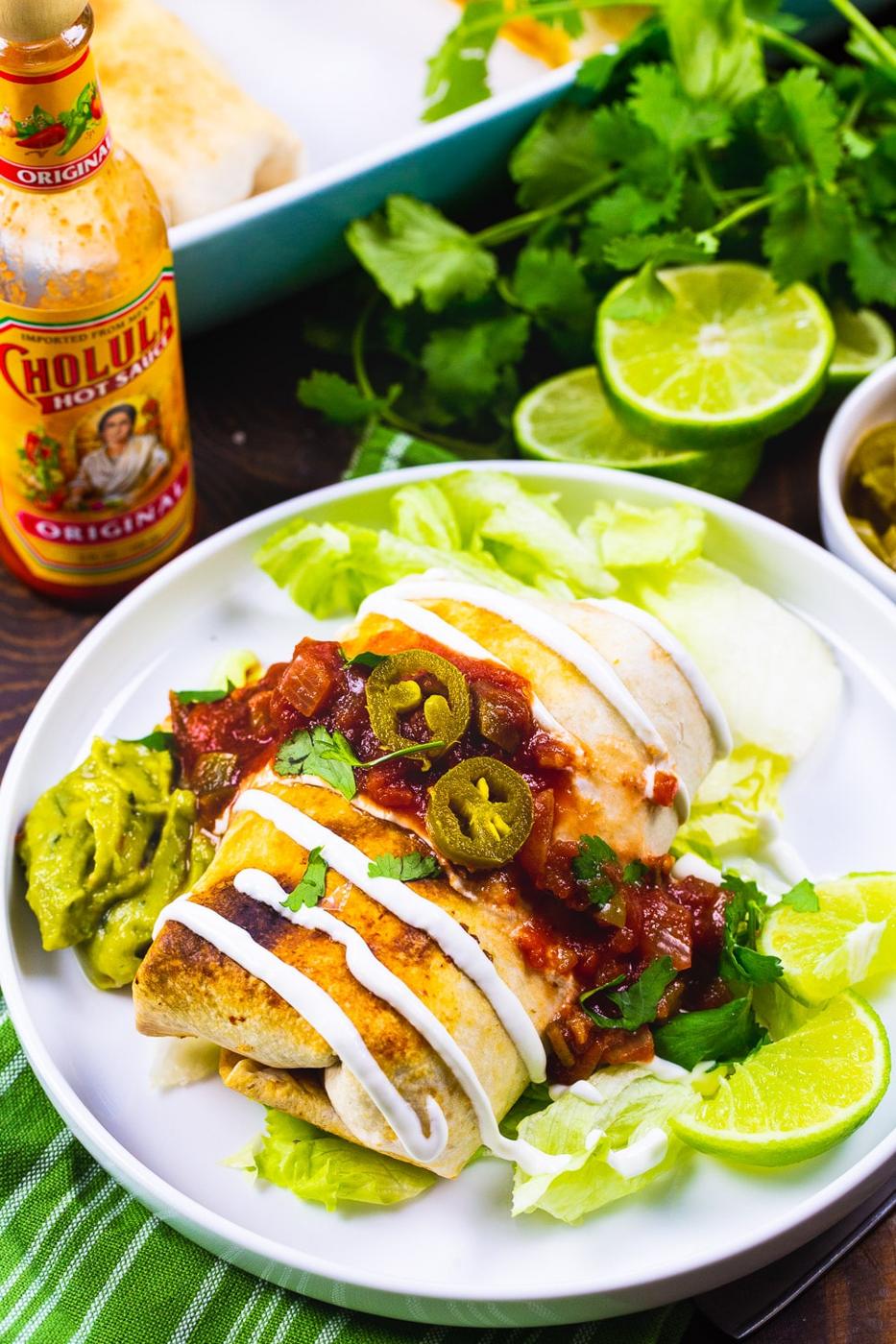 Baked Chicken Chimichangas on a white plate with toppings.