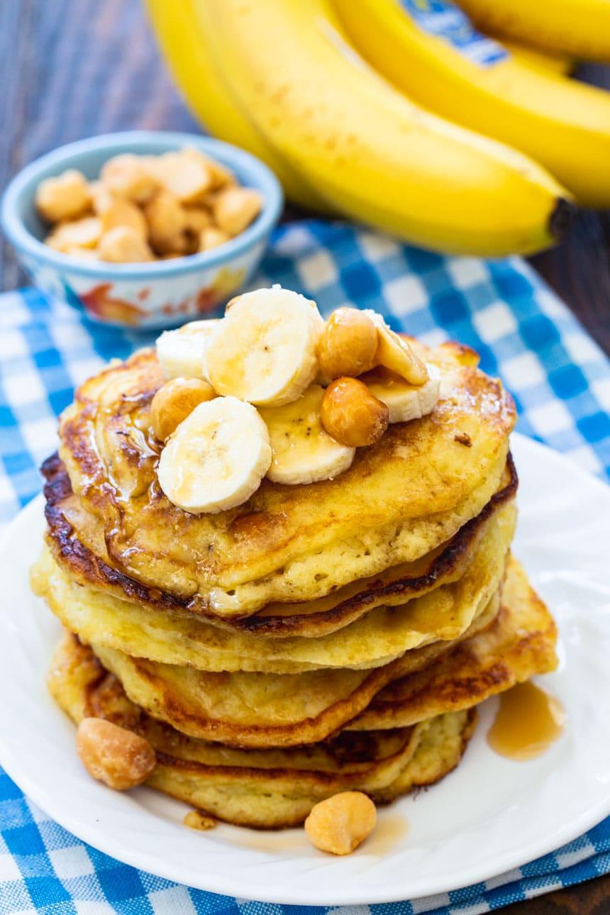 Banana Macadamia Nut Pancakes on a plate with bananas in background.