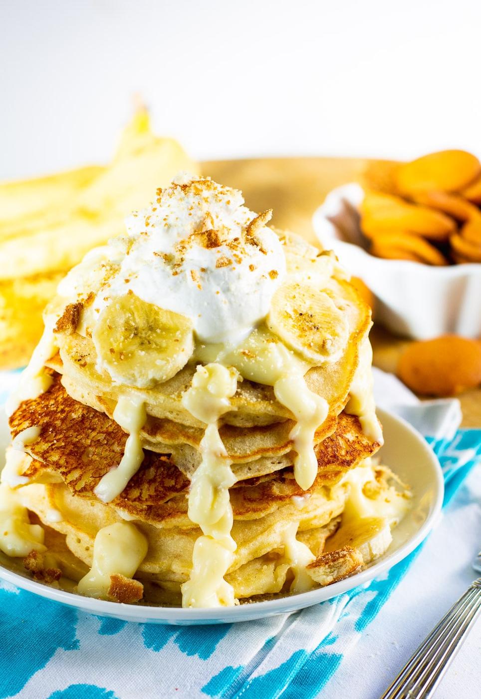 Pancakes on a plate with bananas and vanilla wafers in background.
