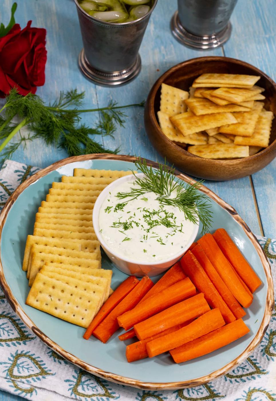 Benedictine dip in a bowl with crackers and carrot sticks.