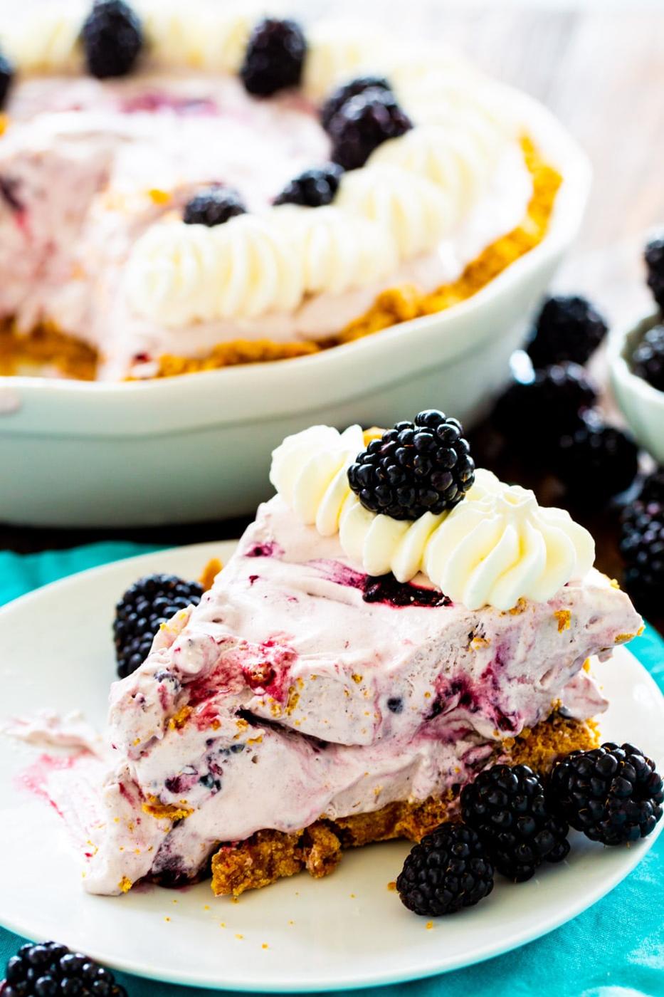 Slice of Blackberry Pie with rest of the pie in background.