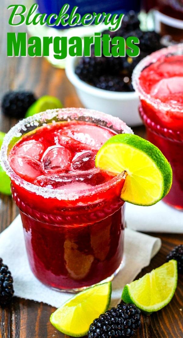 Blackberry Margaritas in a glass with lime wedges and fresh blackberries for decor.