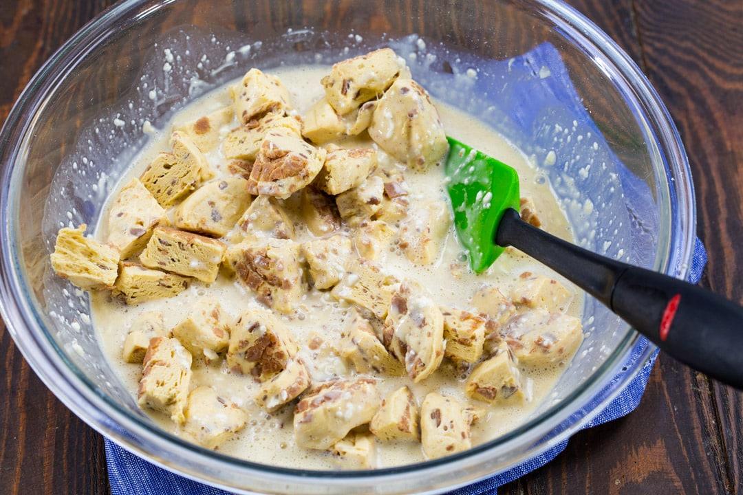 Biscuit pieces mixed with cream cheese mixture in a bowl.