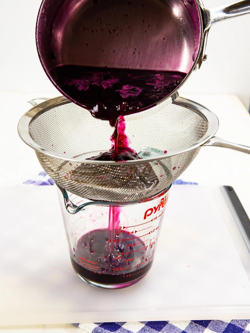 Blueberry simple syrup getting poured through strainer.