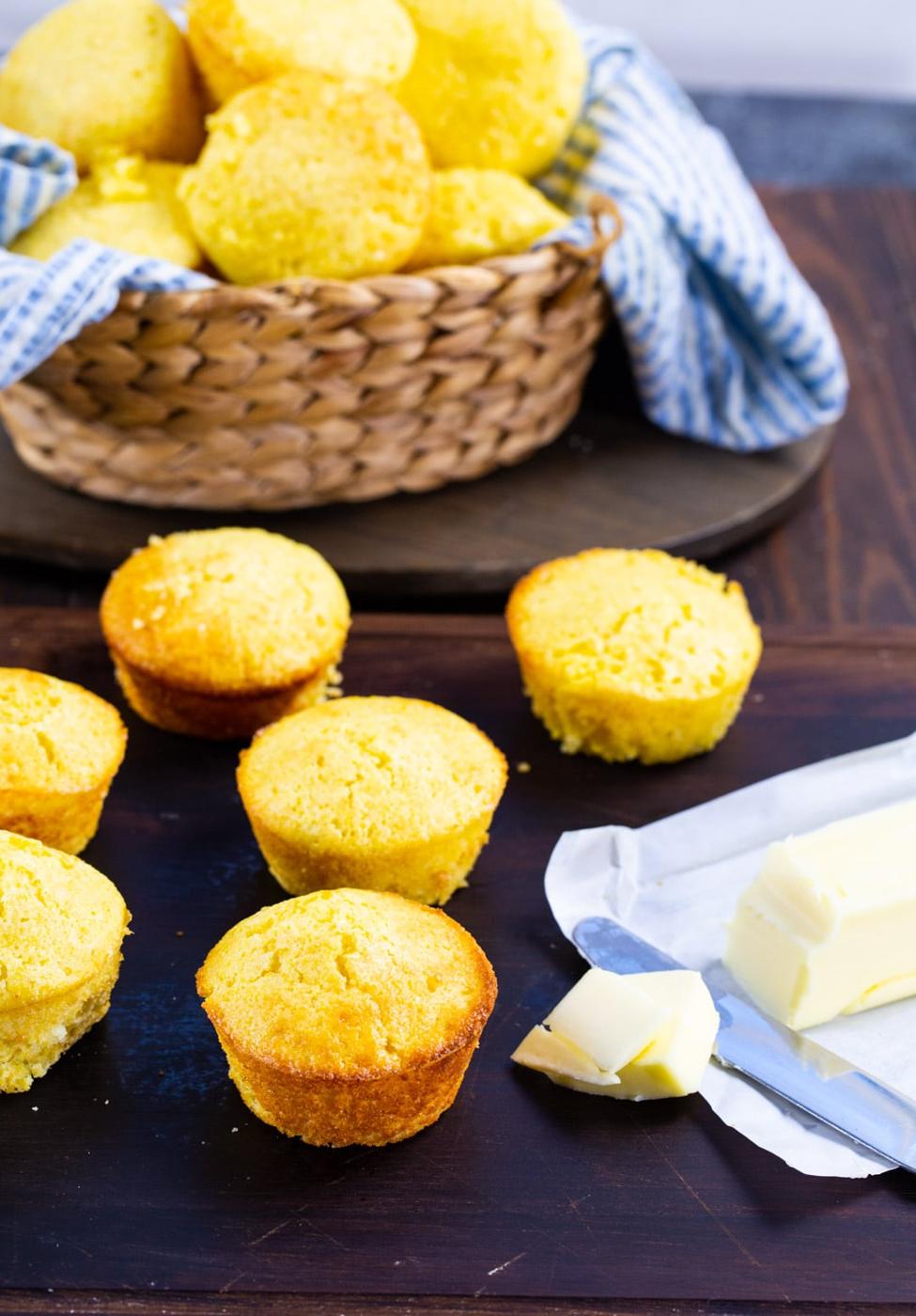 Cornbread muffins on wooden board with stick of butter.
