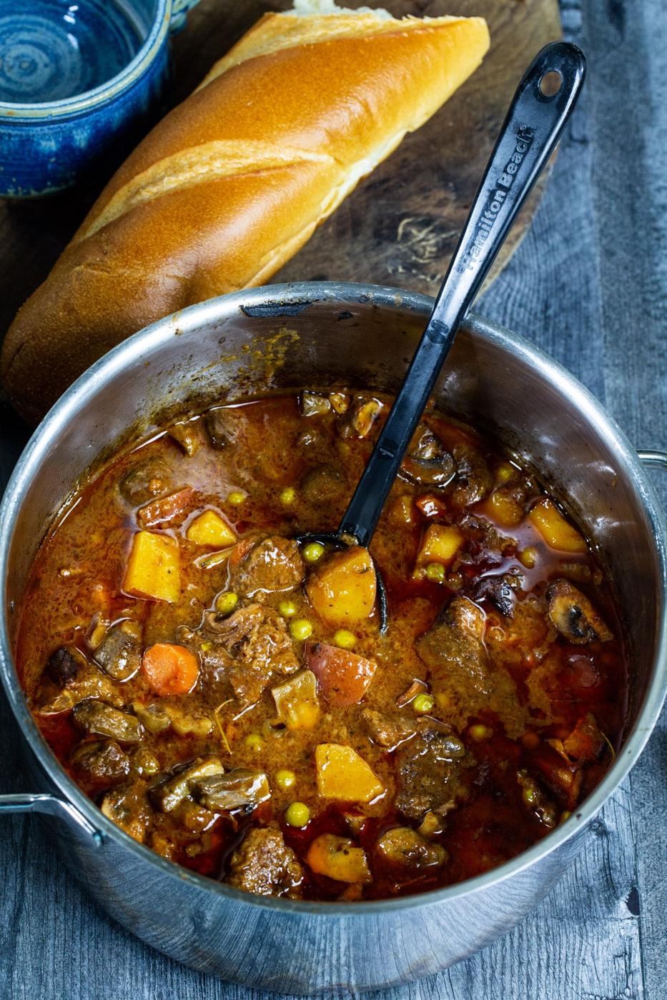Beef Stew in a Dutch oven and loaf of French bread.