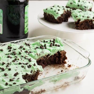 Baking dish with brownies and a bottle of creme de menthe in the background.