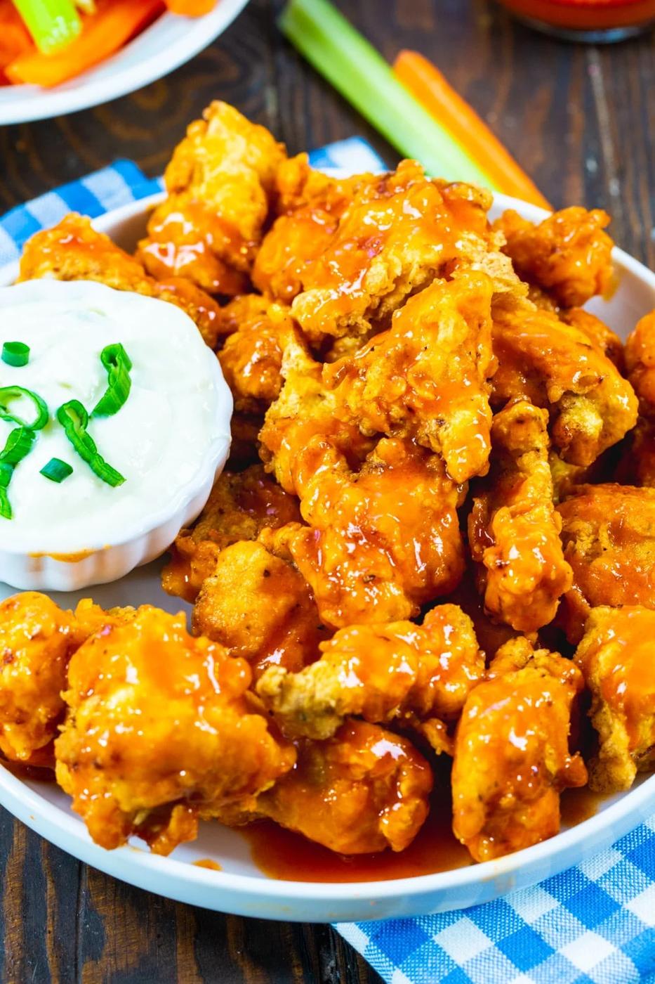 Chicken Nuggets coated in buffalo sauce on a plate.