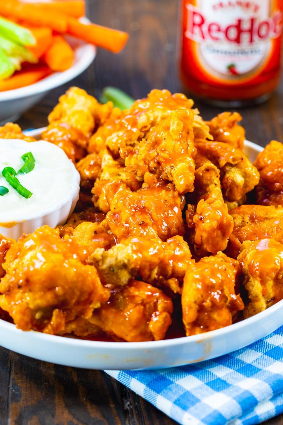 Buffalo Chicken Nuggets on a plate with bottle of hot sauce in background.