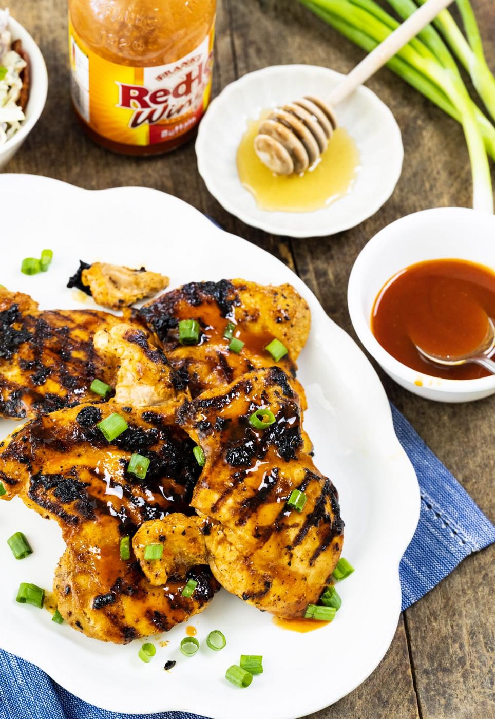 Chicken on platter and bowl of honey and hot sauce.