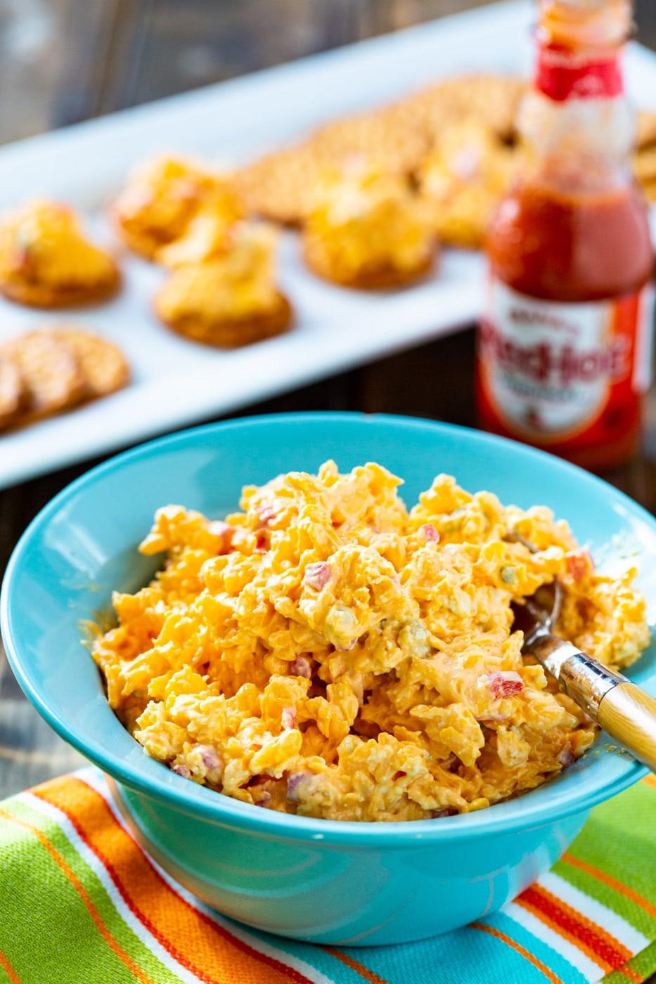 Buffalo Pimento Cheese in a bowl with crackers in background.