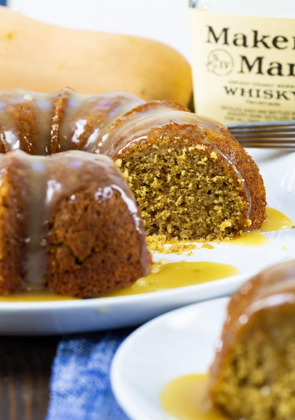 Butternut Squash Cake with Bourbon Glaze with a few slices cut out and bottle of bourbon.