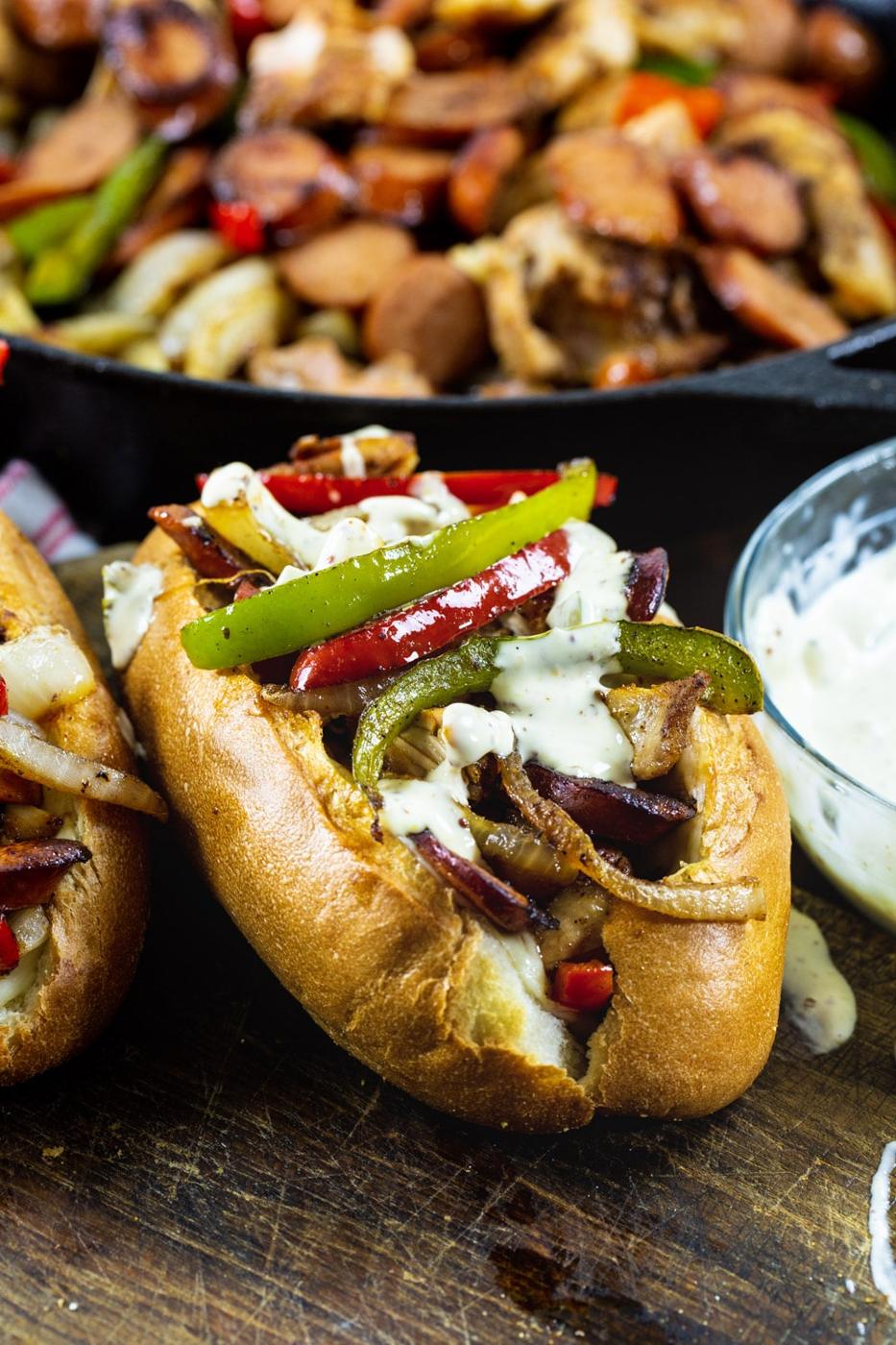 Cajun Chicken and Andouille Subs with skillet full of chicken and sausage filling in background.