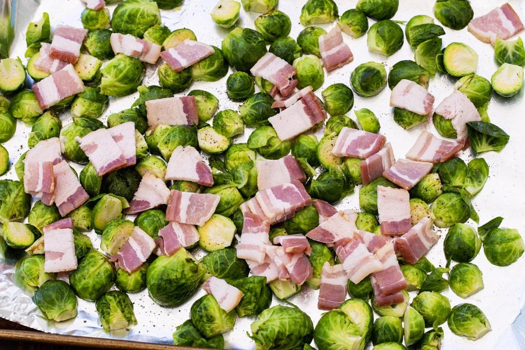 oncooked brussels sprouts and bacon on baking sheet.