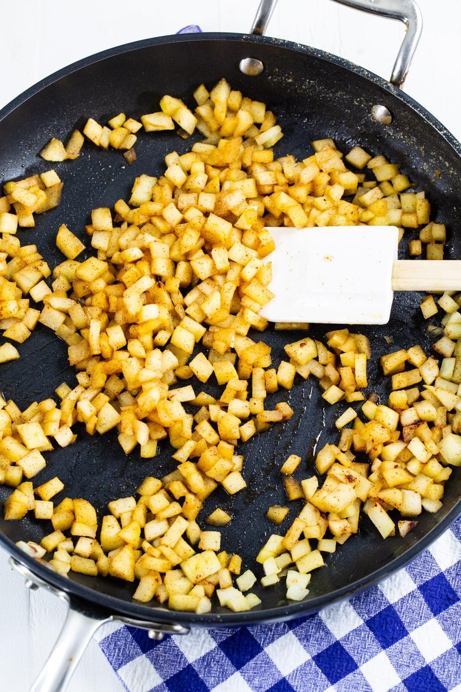 Diced apple cooking in skillet.