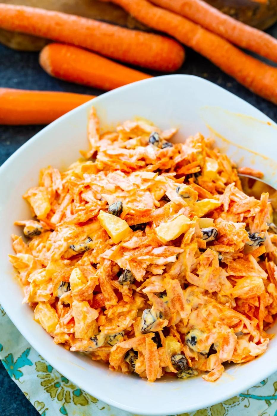 Carrot Salad in bowl surrounded by fresh carrots.