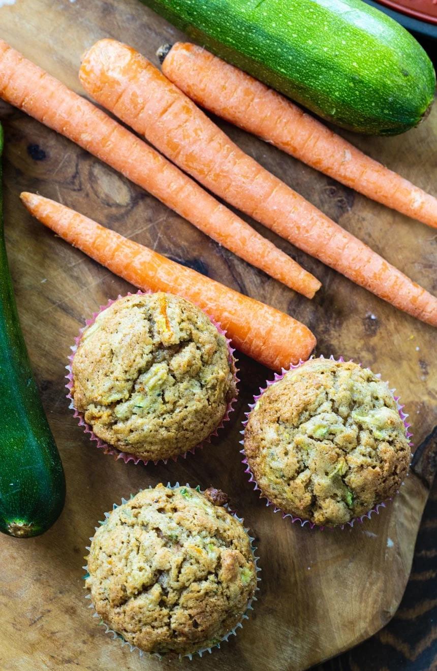 Overhead shot of 3 Zucchini Carrot Muffins with carrot sticks.