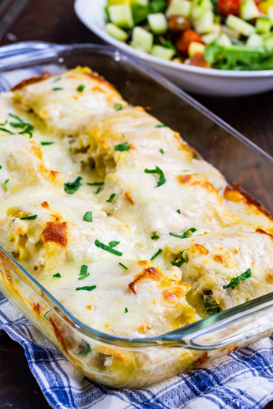 Chicken Alfredo Lasagna Roll-Ups in baking dish and bowl of salad.