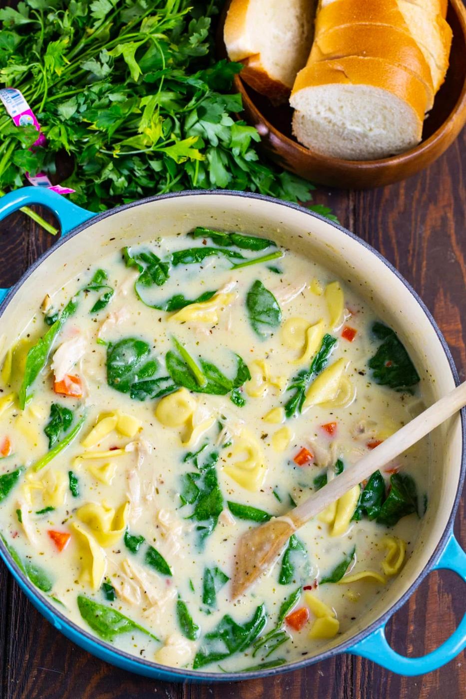 Tortellini Soup in a Dutch oven and small plate of fresh breand.