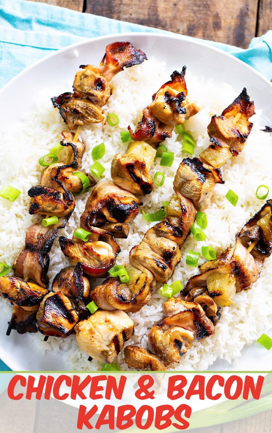 Chicken and Bacon Kabobs over white rice on a serving plate.