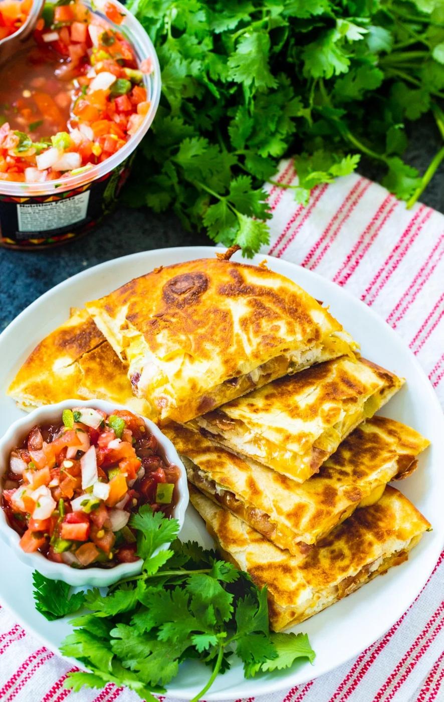 Quesadilla triangles on plate with bowl of pico de gallo.