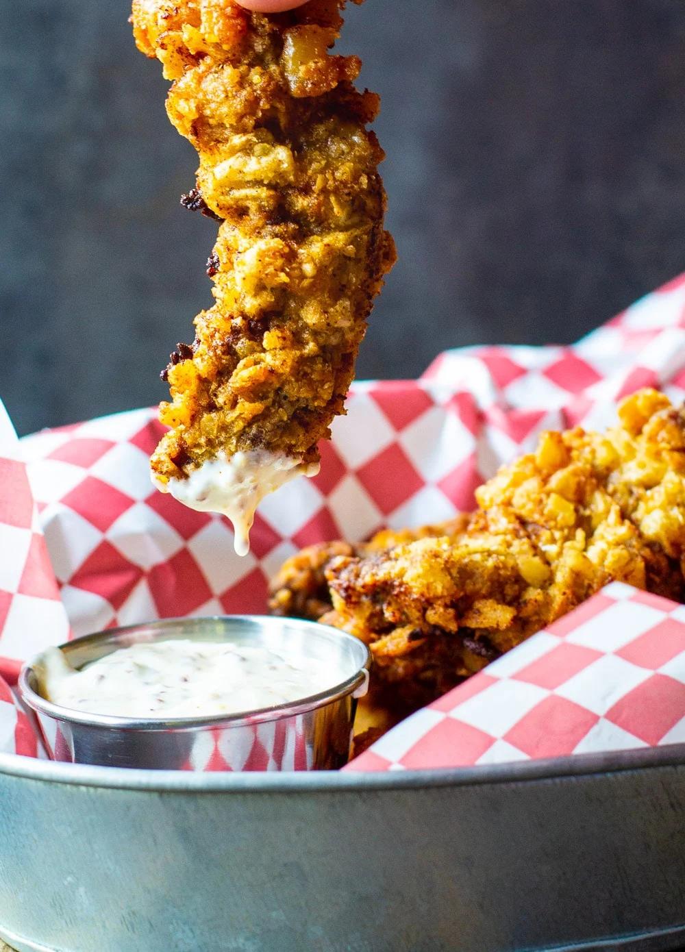 Chicken Fried Steak Fingers being dipped in sauce.