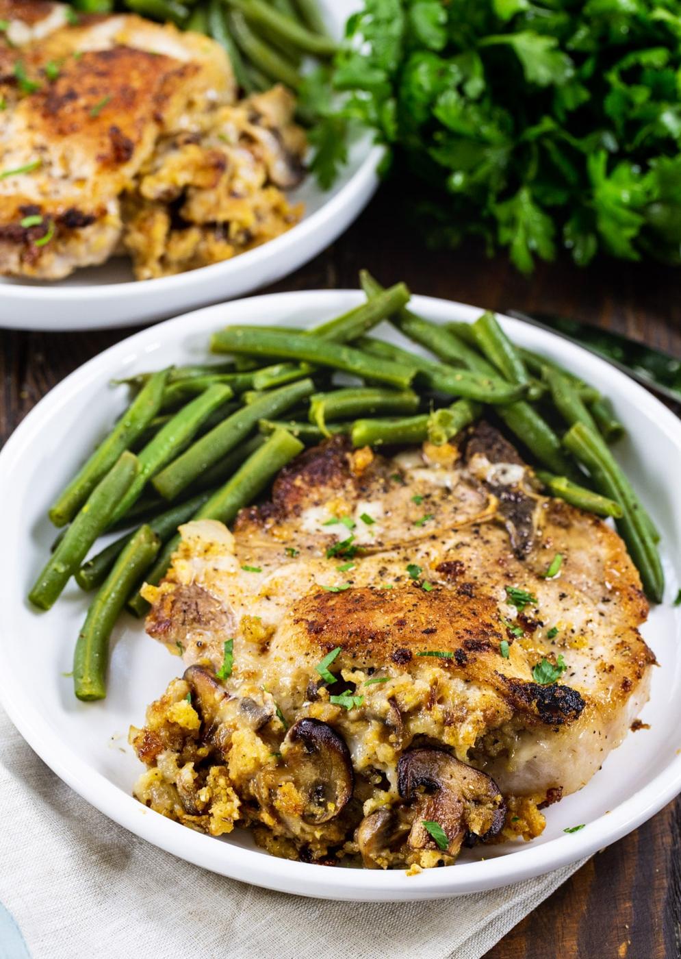 Cornbread Stuffed Pork Chops and green beans on a plate.