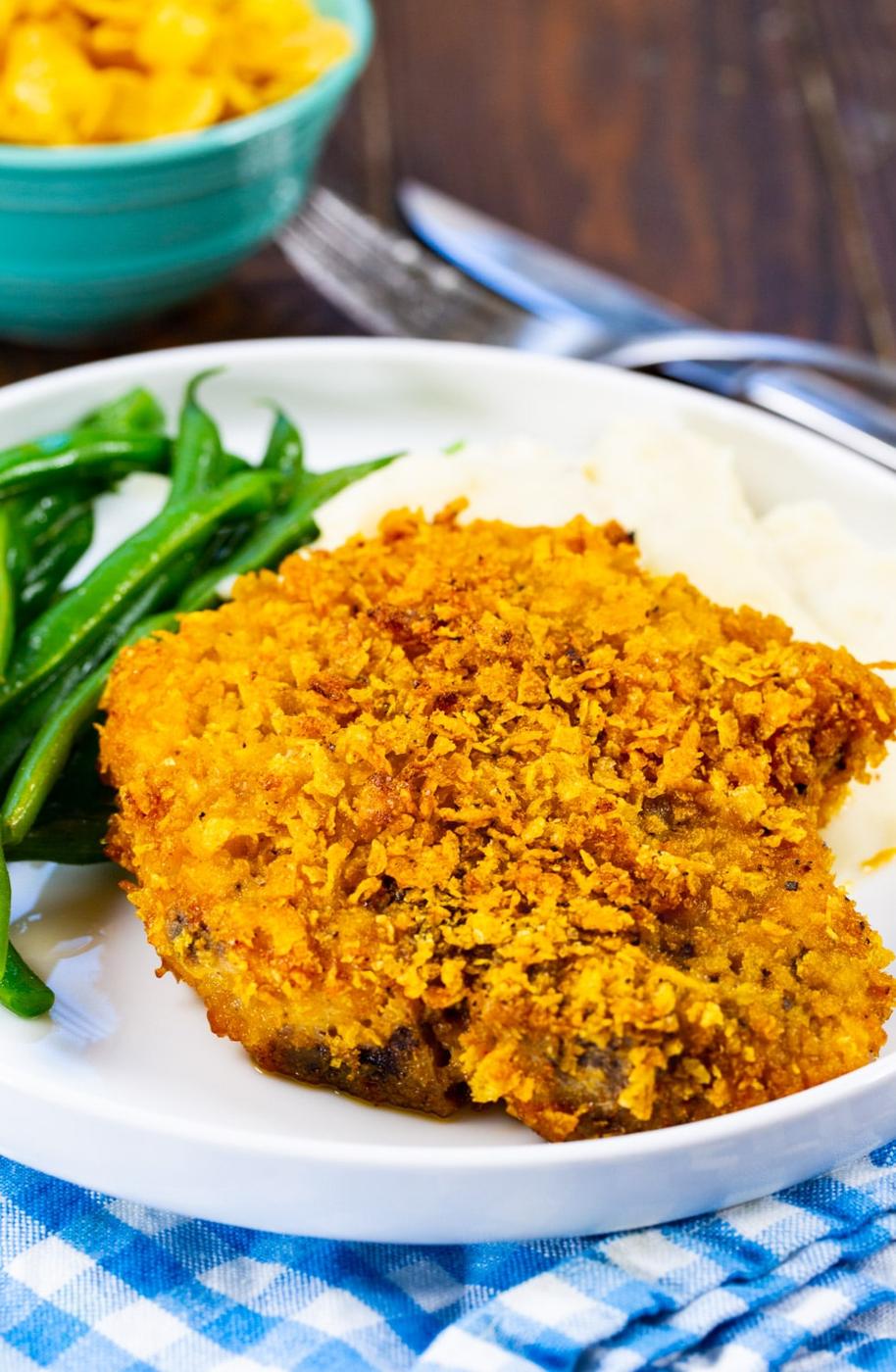 Cornflake Crusted Baked Pork Chop on plate with mashed potatoes and green beans.