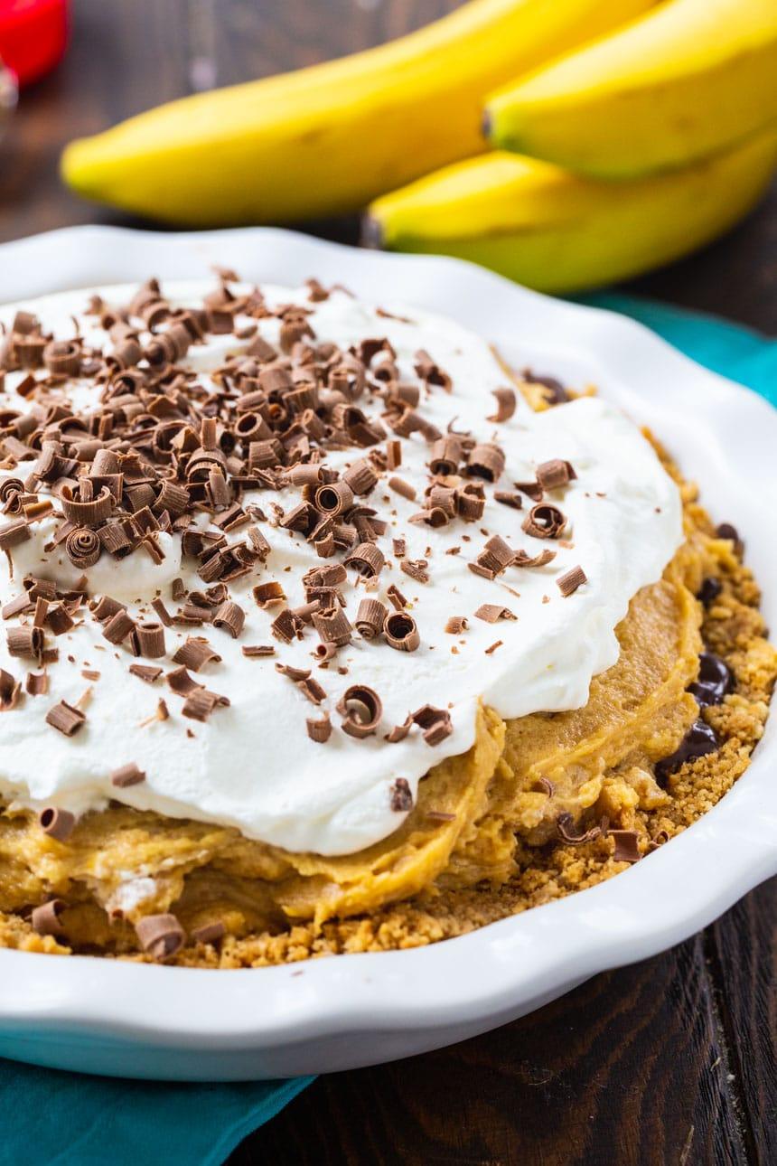 Peanut Butter Banana Pie in a white pie plate with bananas in the background