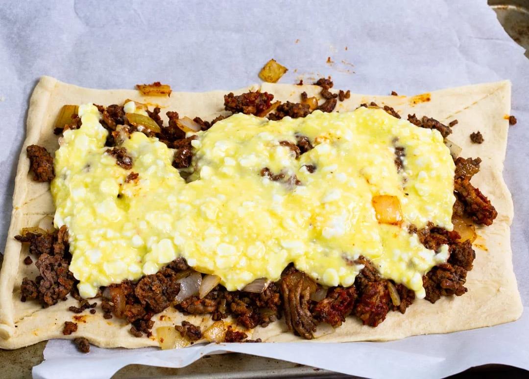 Meat and cheese layer on crescent dough.