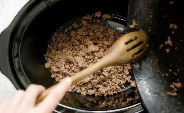Ground beef being transferred to slow cooker.