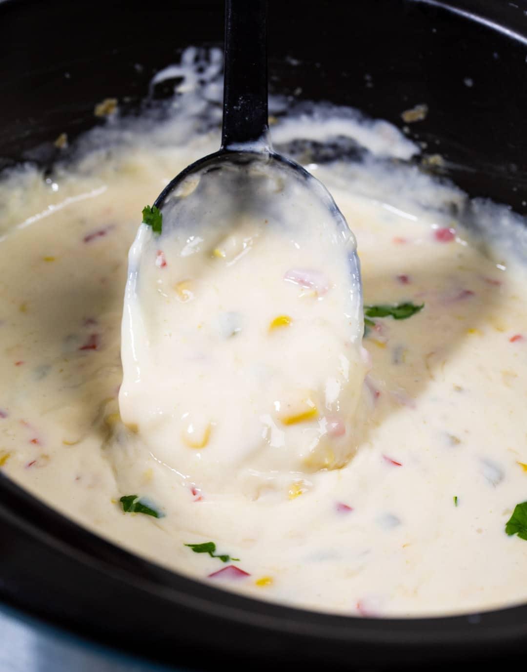 Crock Pot Queso Blanco getting scooped up with a spoon.