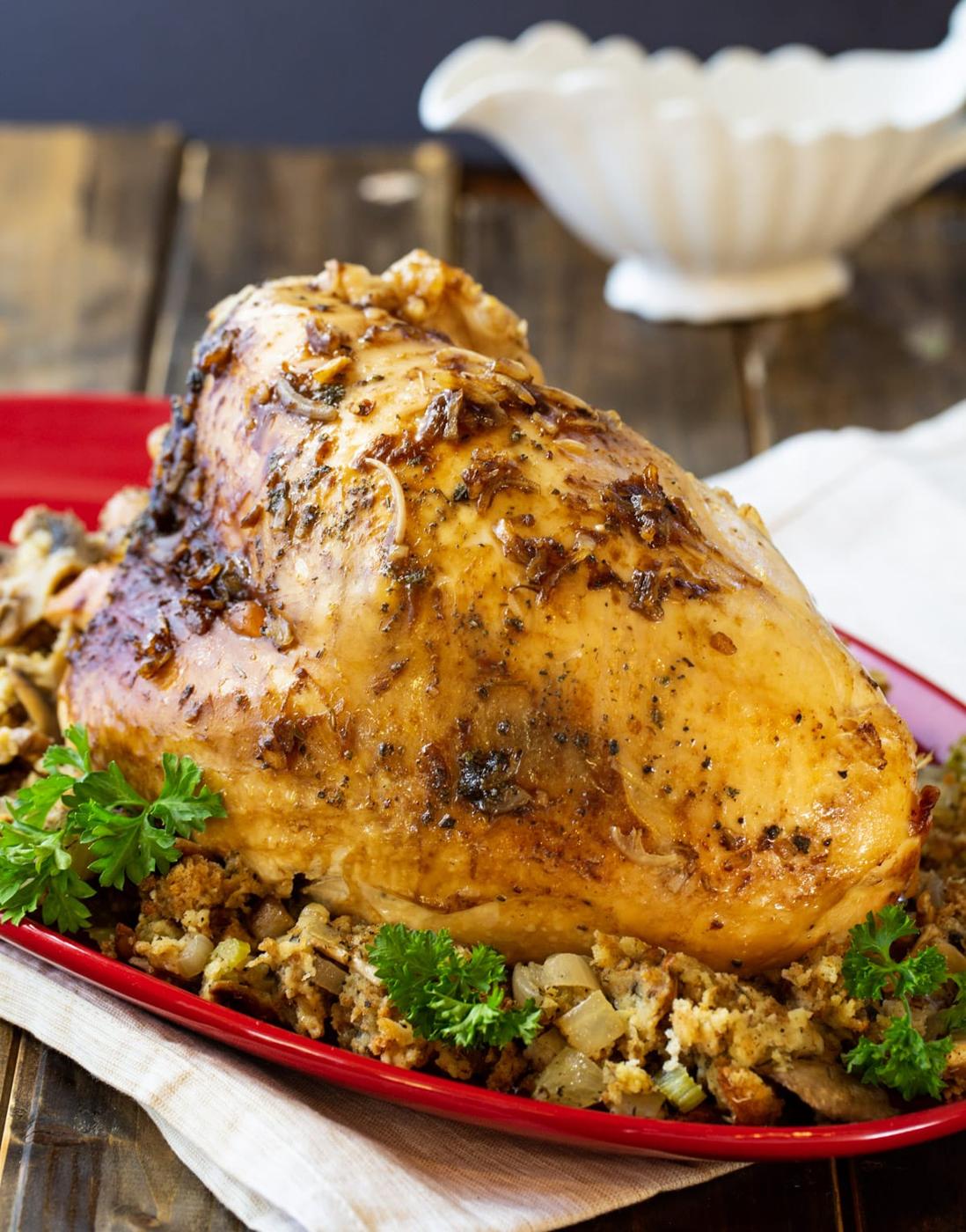 Whole turkey breast on top of stuffing on a platter.