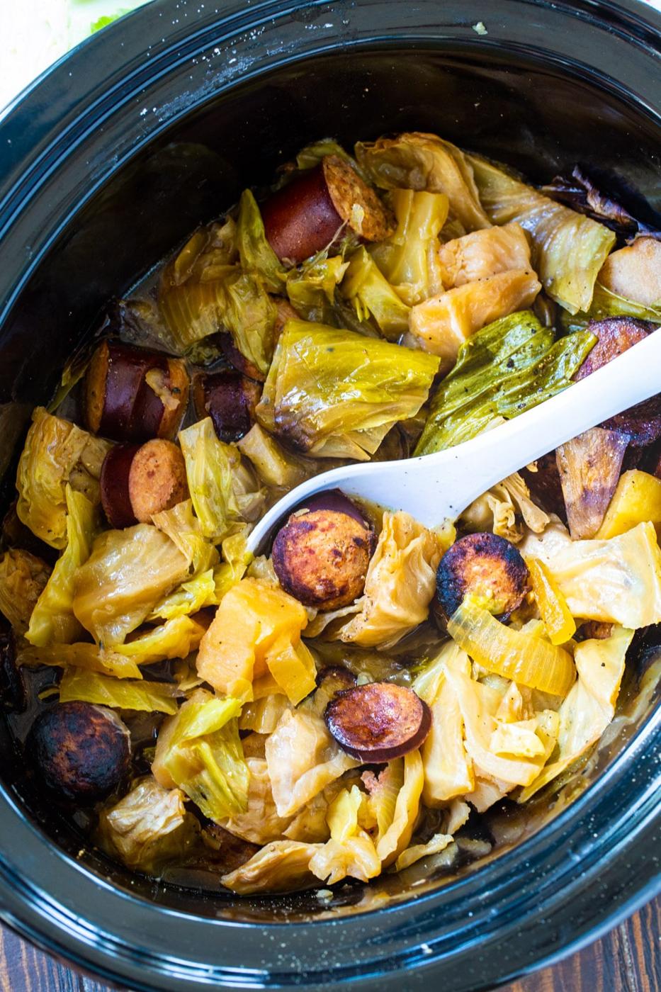 Spoon scooping cabbage and kielbasa out of crock pot.
