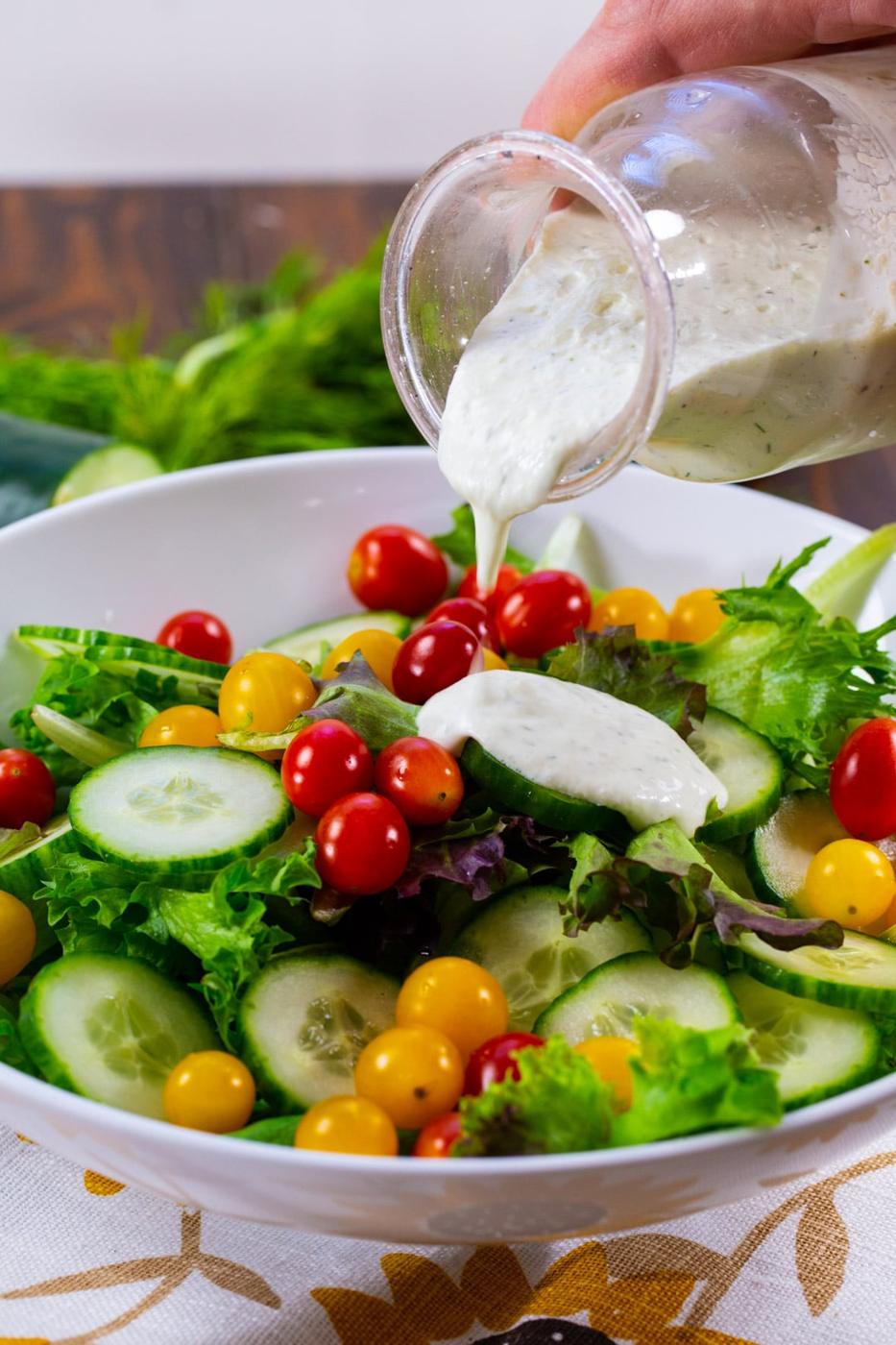 Cucumber Dill Dressing getting drizzled on salad.