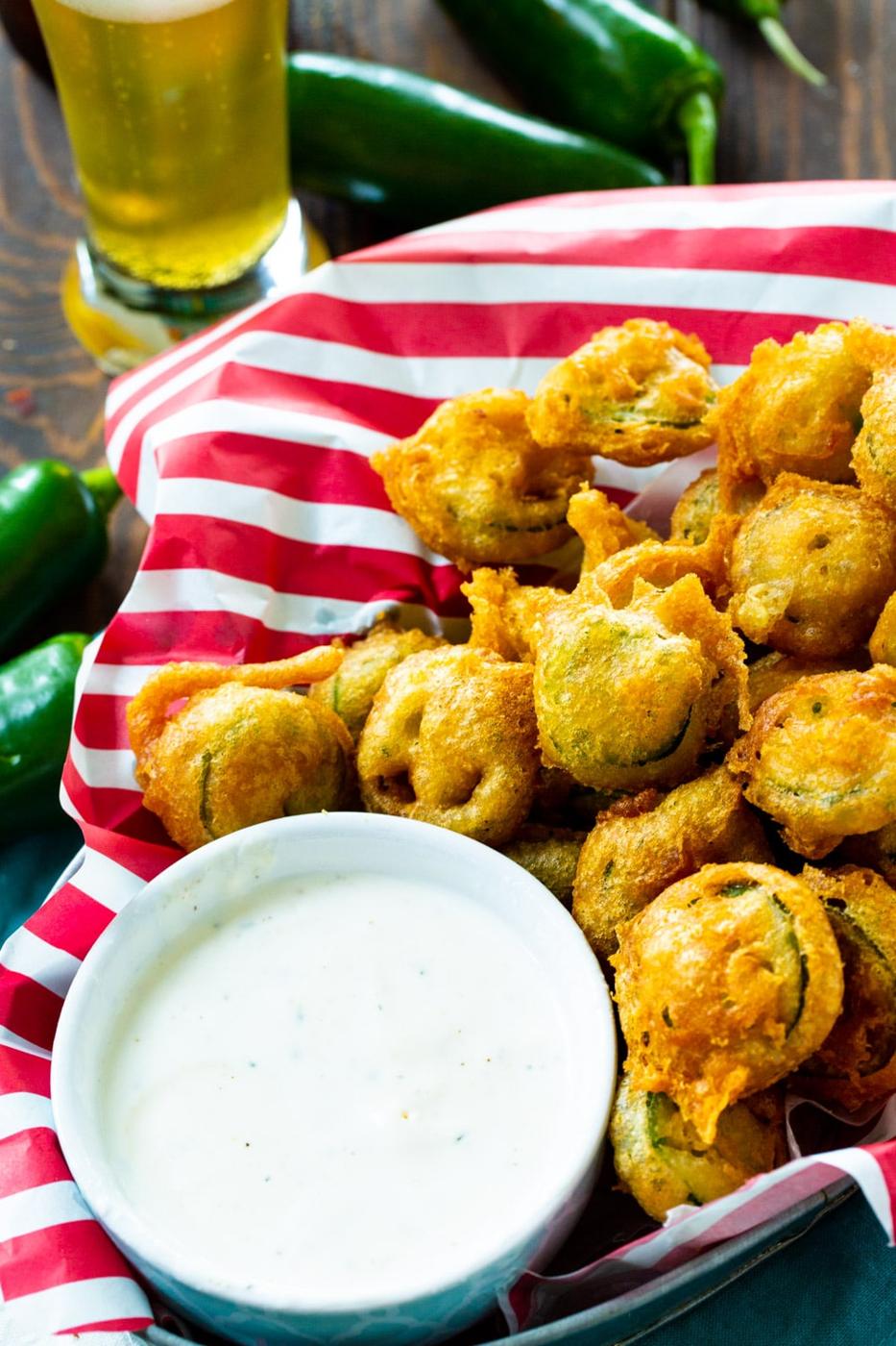 Fired Jalapenos in basket surrounded by fresh jalapenos.