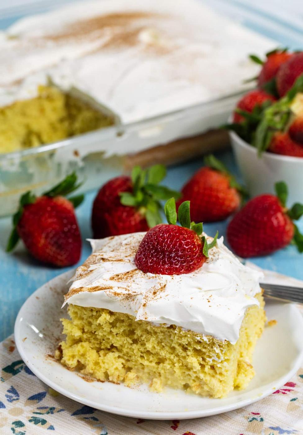 Slice of cake on plate with rest of cake in background.