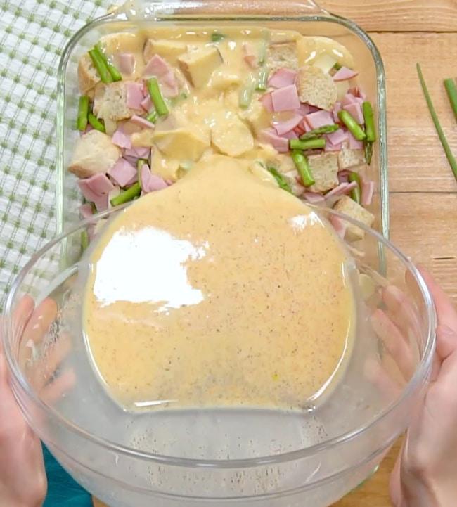 Pouring egg mixture over casserole.