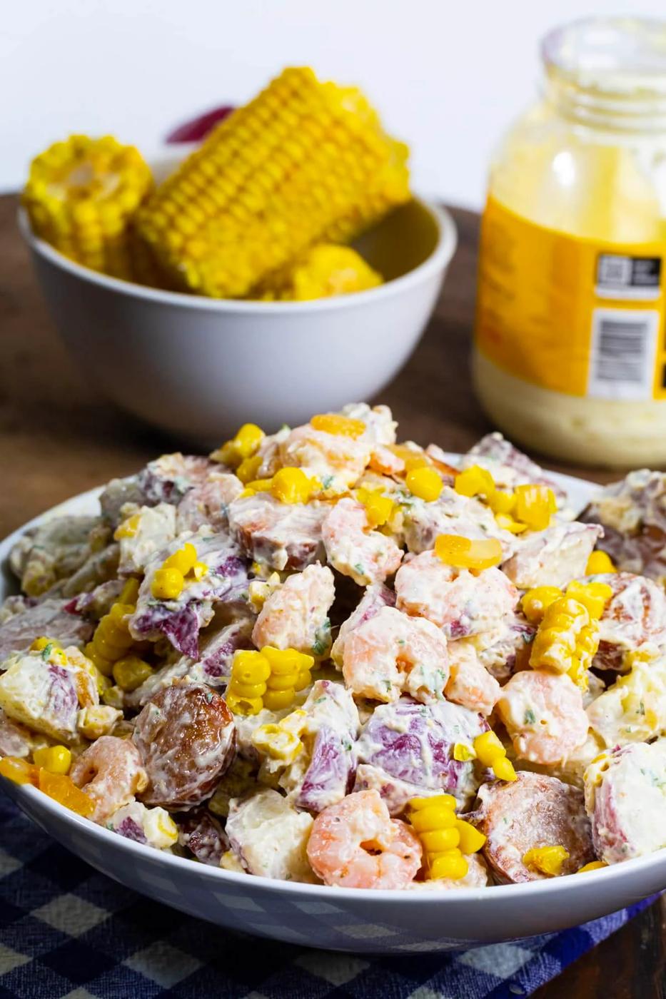 Frogmore Potato Salad in a large bowl with bowl of corn on the cob in background.