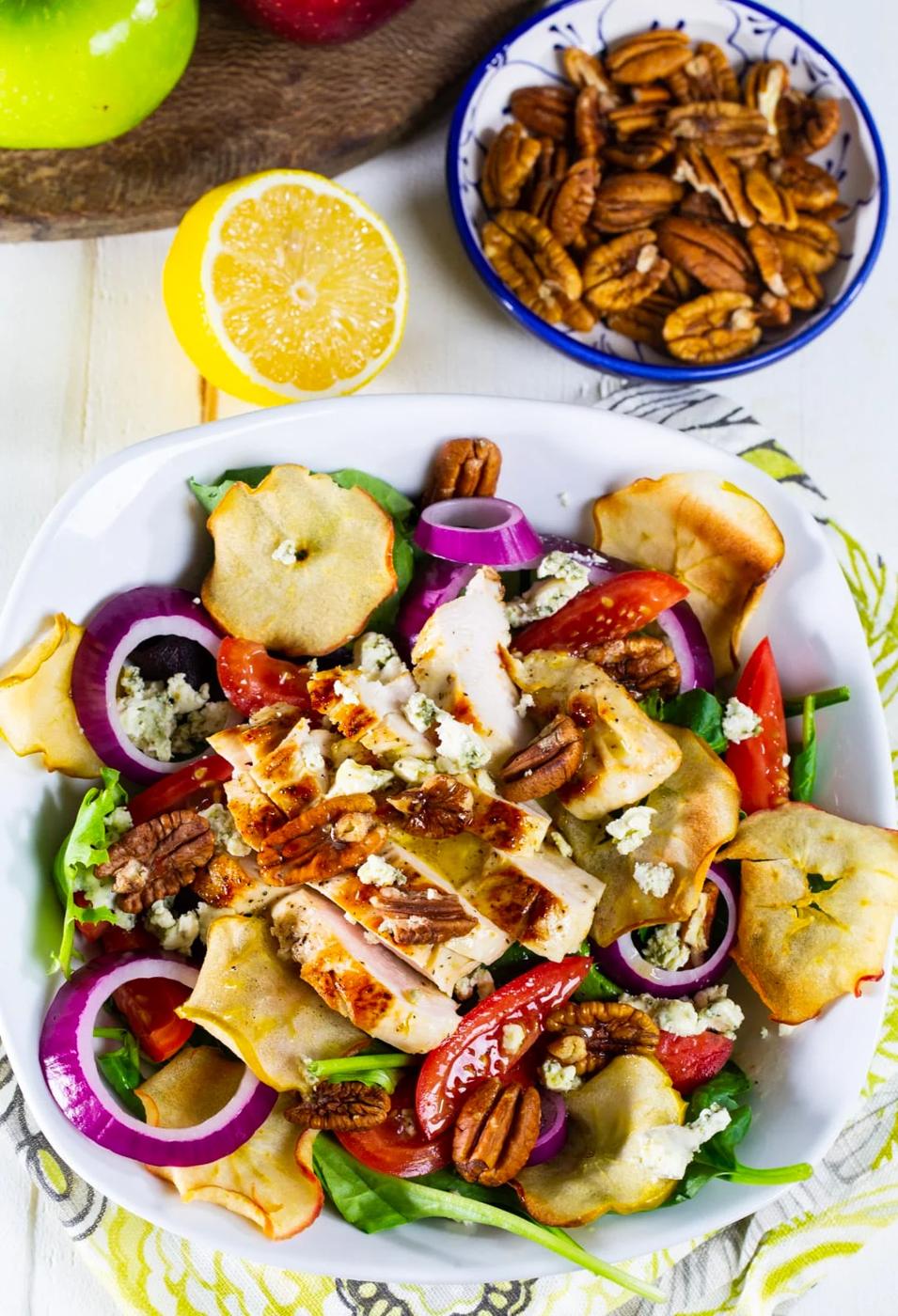 Salad in a bowl and a bowl full of pecans.