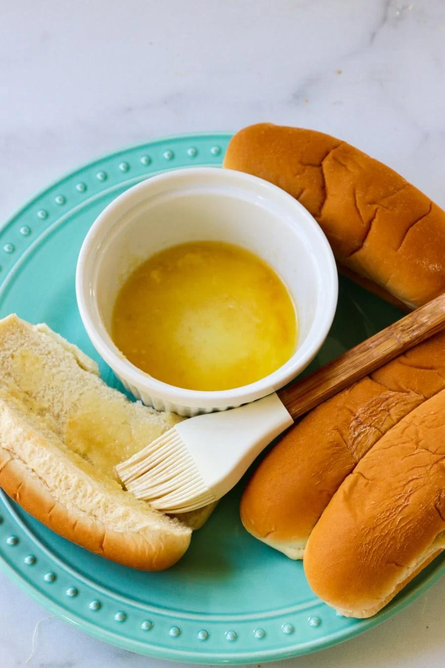 Buns getting brushed with melted butter.