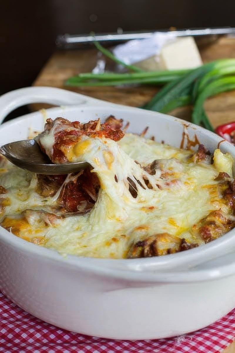 Spoon scooping casserole out of baking dish.