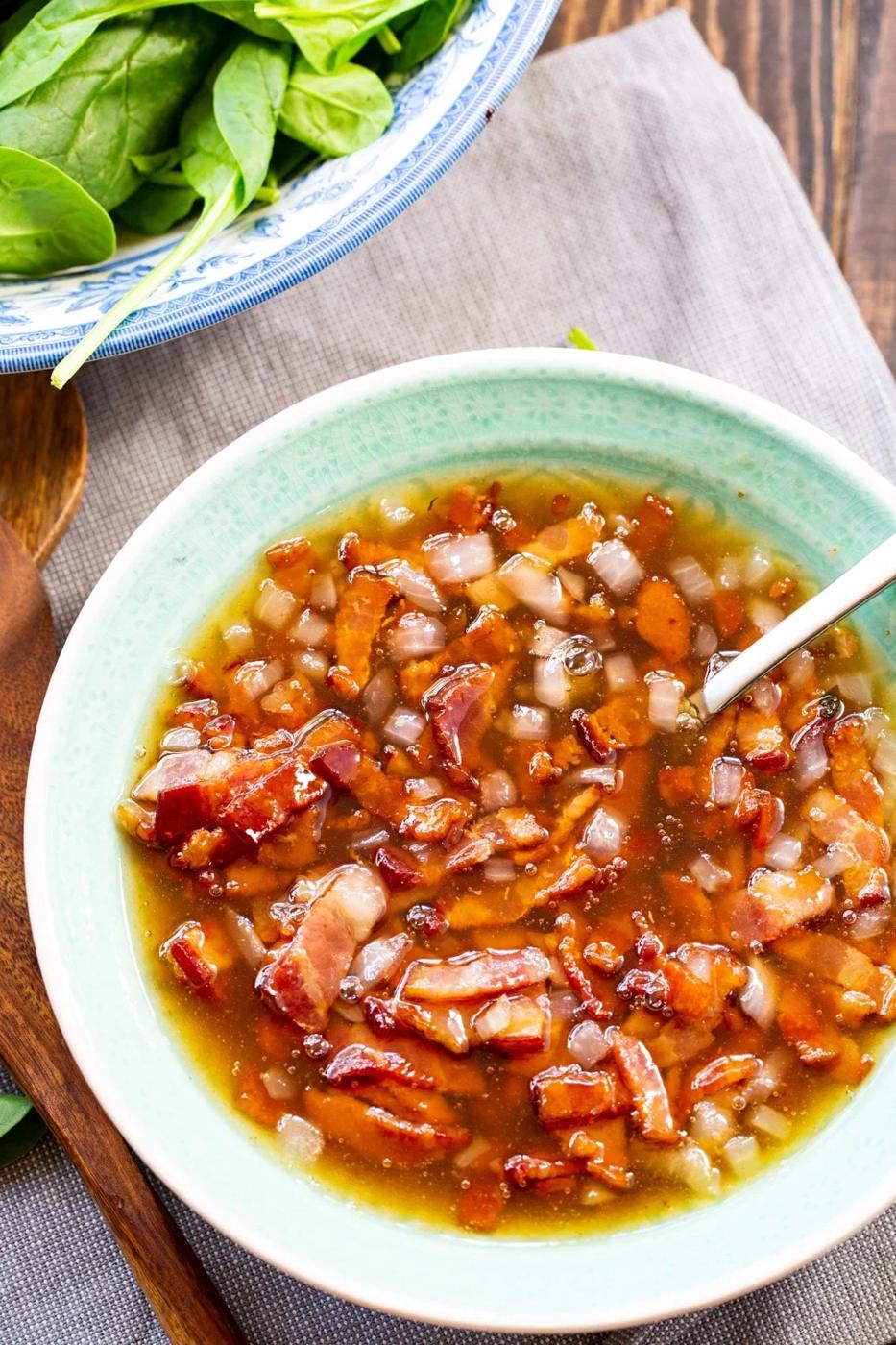 Hot Bacon Dressing in bowl with a spoon.