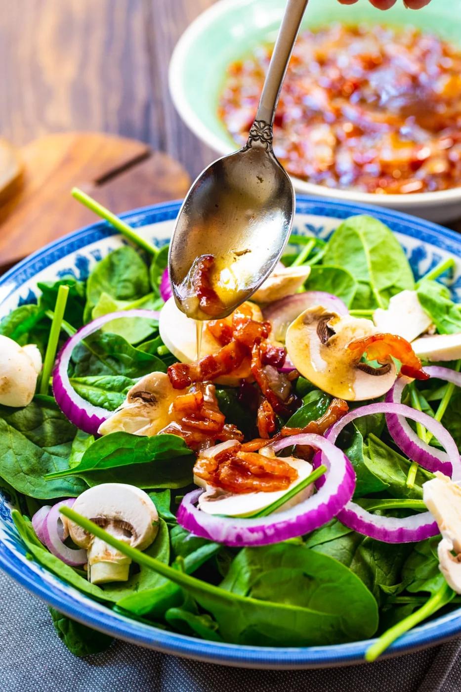 Dressing being spooned over salad.