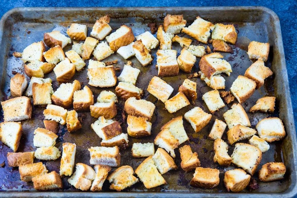 Toasted bread cubes on baking sheet.