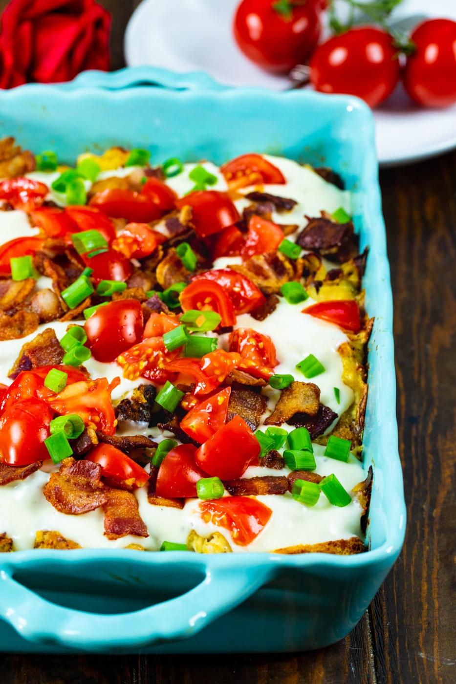 Hot Brown Casserole covered with tomatoes and bacon.