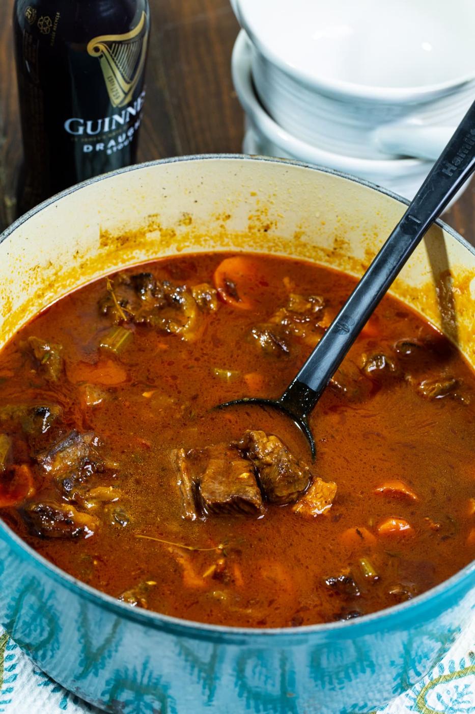 Stew in a Dutch oven and bottle of beer.