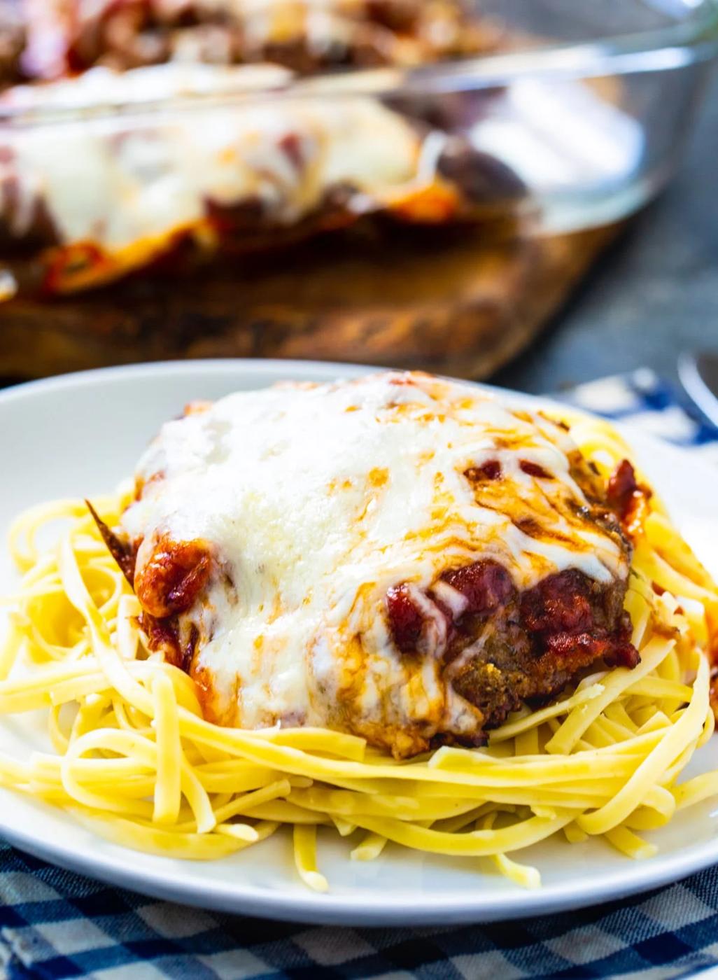 Cubed steak covered in cheese on top of spaghetti