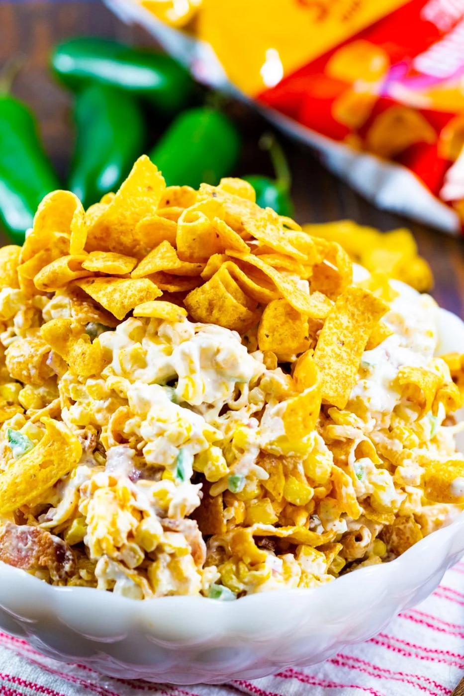 Jalapeno Popper Corn Frito Salad in white serving bowl with jalapenos in background.
